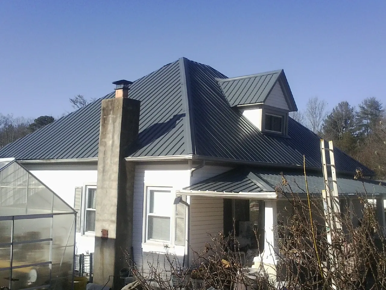 Dark blue standing seam metal roof on a white farmhouse with dormer — Slate & Tile Roof Repair by Roofing Brothers in Lyle