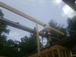 Carpenter setting a ridge beam over a new addition frame — Ice Dam Removal by Roofing Brothers in Lyle