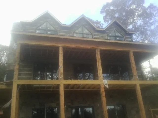 Dormers and porch framing on a large log home under construction — Roof Coating work by our crew in Lyle