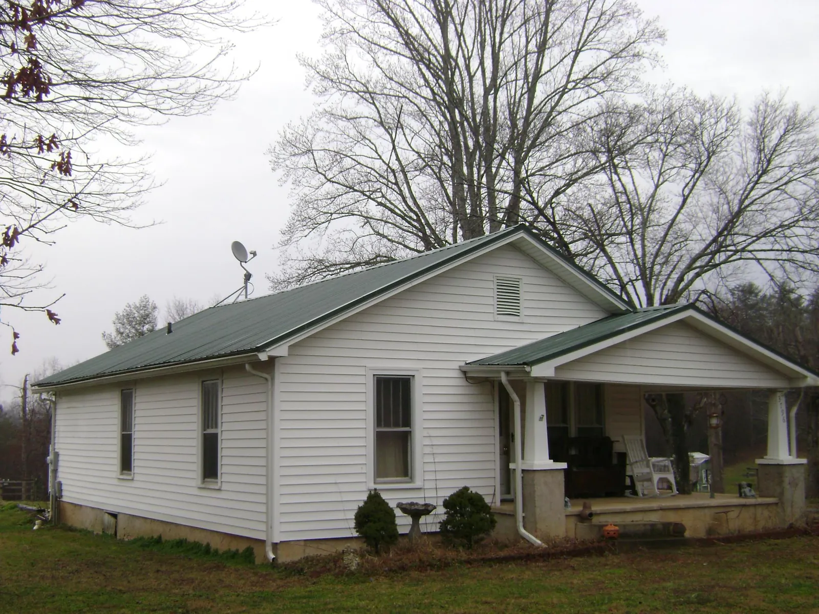 Green metal roof on a white bungalow with a side porch in Lyle