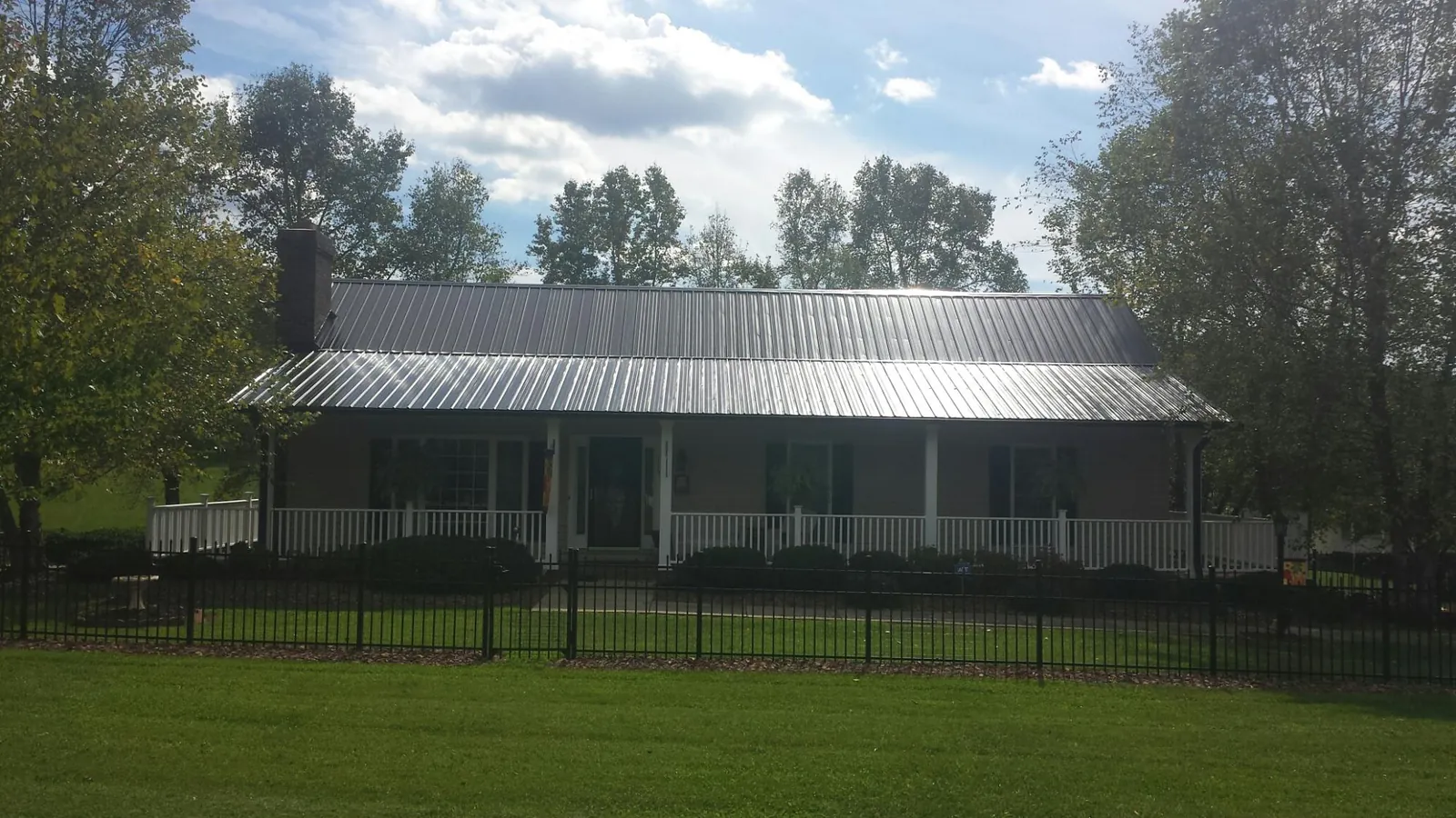 Gray metal roof on a brick ranch with a full width front porch — Gutter Guard Installation work by our crew in Lyle